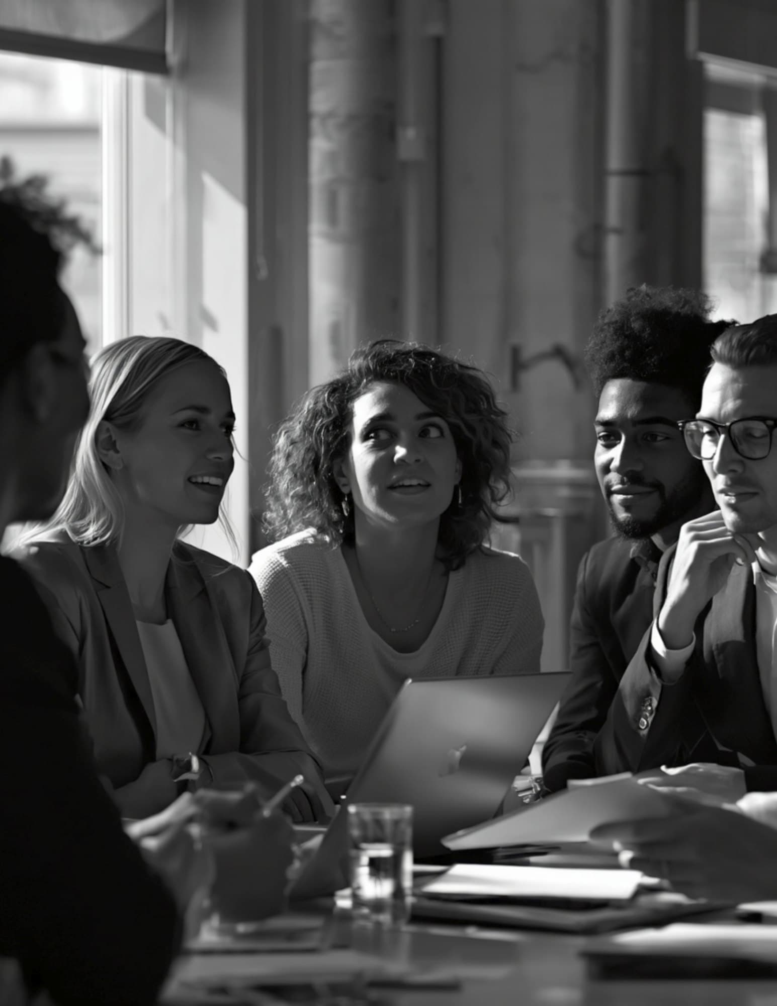 Marketing leaders in conversation around a laptop in a meeting room